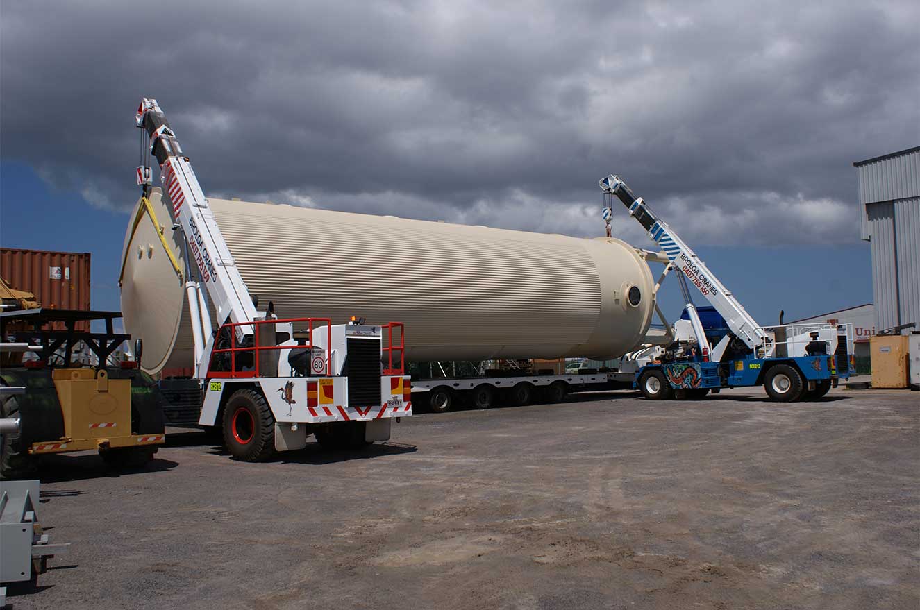 Moving a large industrial fuel tank with two cranes to get onto a truck