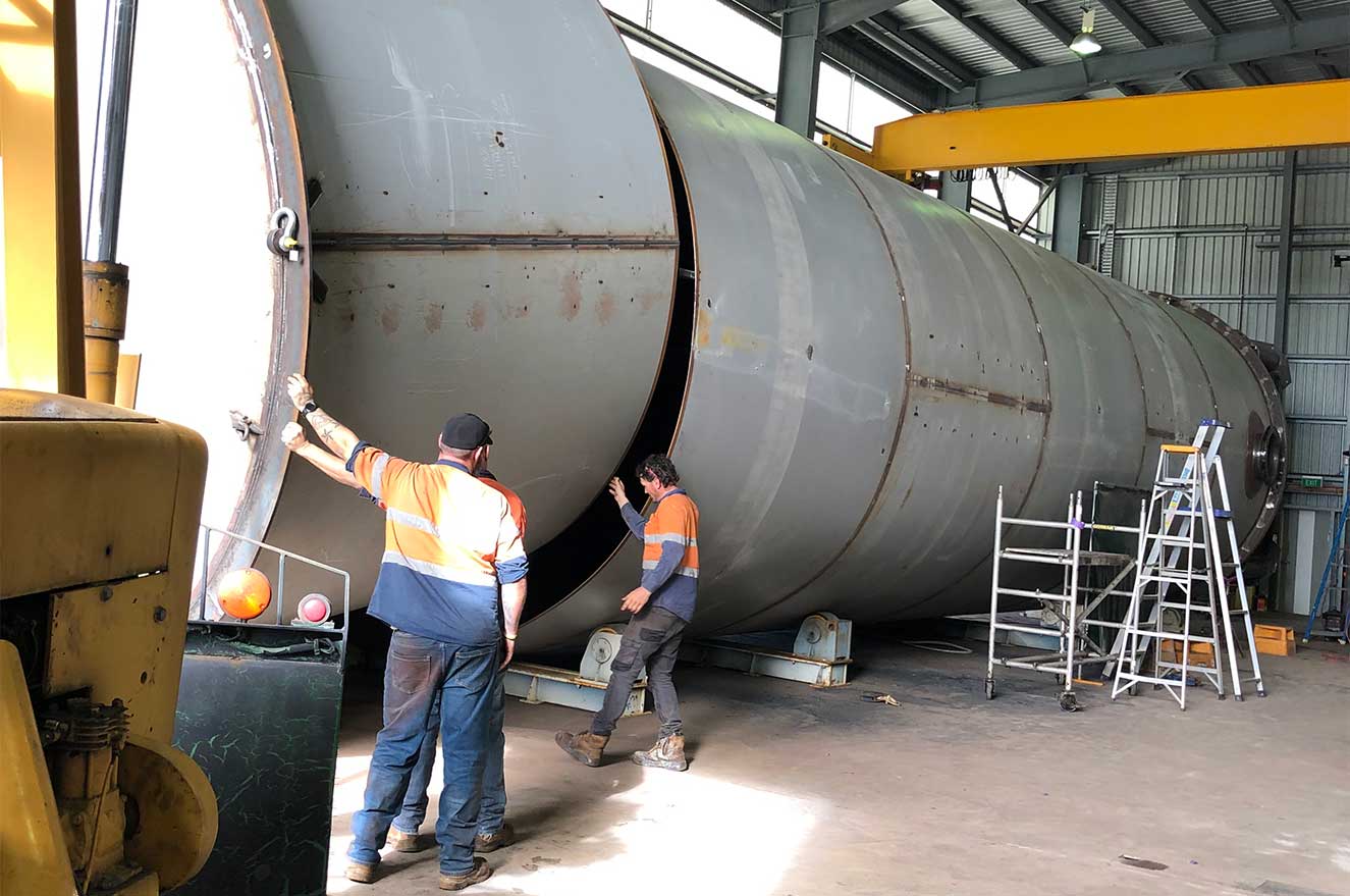 Building a large 270 000 litre fuel tank. One tradie directing two sections to be joined together