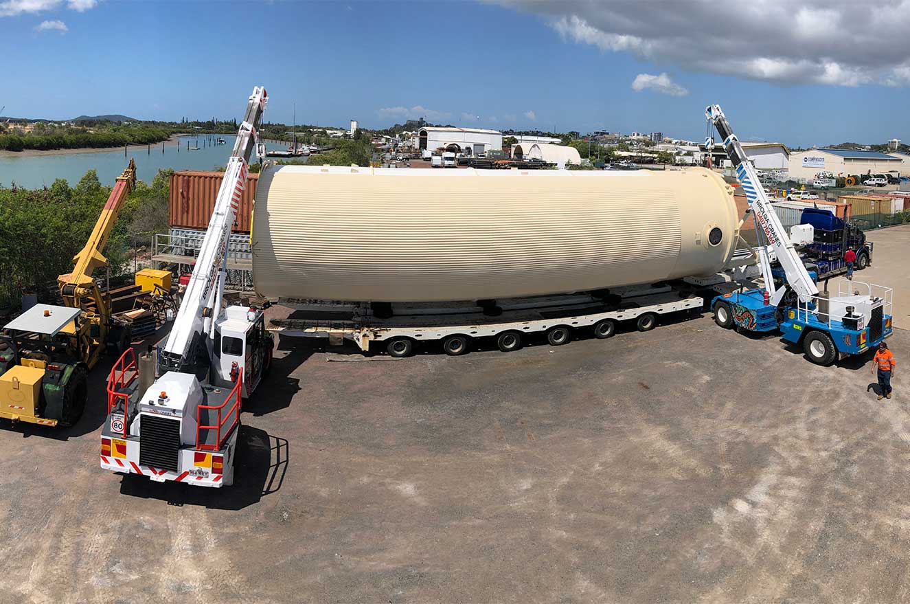 Moving a large industrial fuel tank with two cranes to get onto a truck